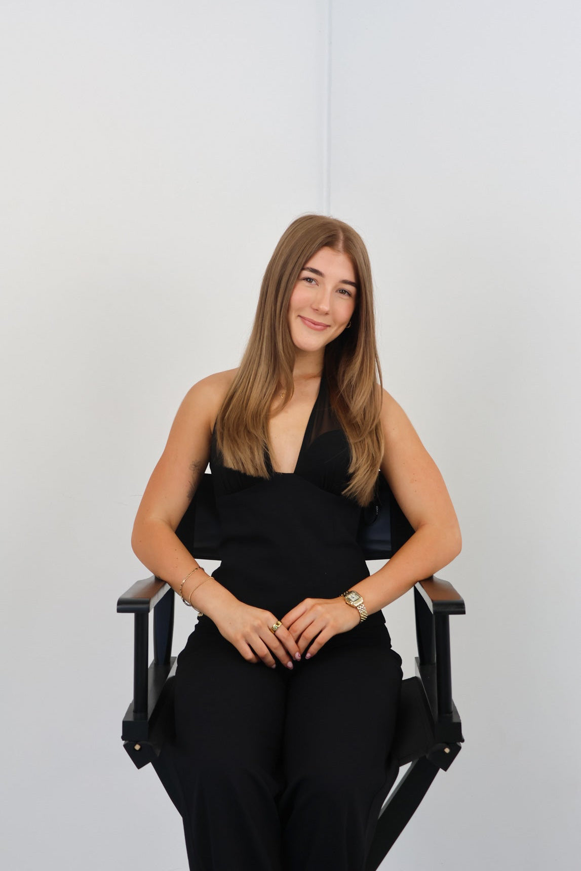 Woman sitting on a director's chair against a white background
